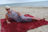 At the beach in my grey loose fitting dress which gets blown about in the wind to reveal my shaved pussy and you can see